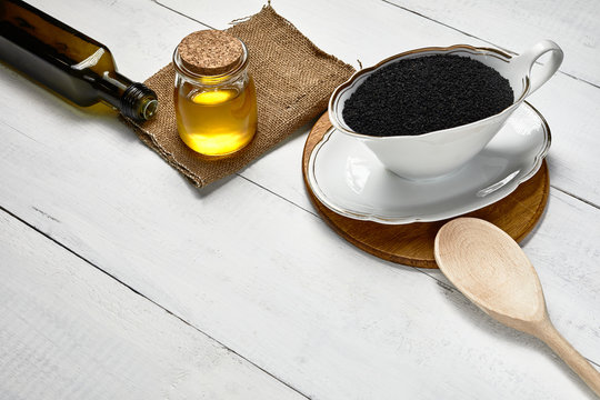 Black cumin seed in ceramic bowl on the table, Cold pressed oil in glass jar and bottle.