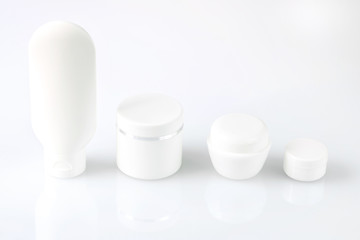 White tubes and jars for cream and lotion on a white background. Spa face and body care.