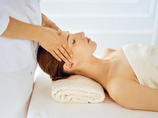 Beautiful woman enjoying facial massage with closed eyes. Spa treatment concept in medicine