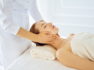 Obraz na płótnie Canvas Beautiful woman enjoying facial massage with closed eyes. Spa treatment concept in medicine