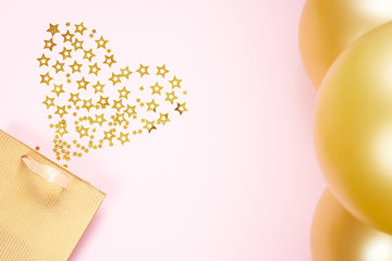 Valentines Day background concept. Golden paper gift bag, small stars in the shape of heart and gold Balloon. flat lay.