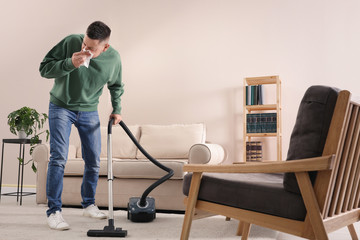 Man with dust allergy cleaning his home - obrazy, fototapety, plakaty