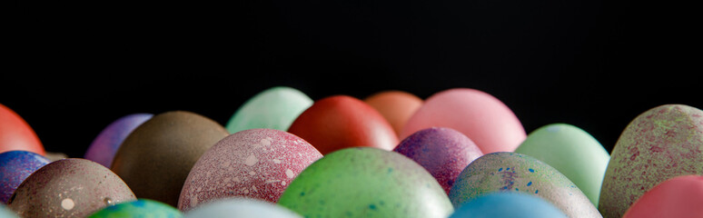 Selective focus of colorful Easter eggs isolated on black, panoramic shot