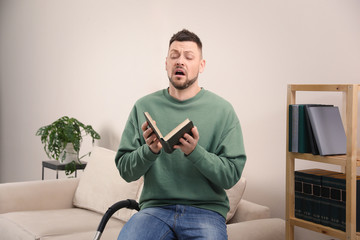 Man with book suffering from dust allergy at home