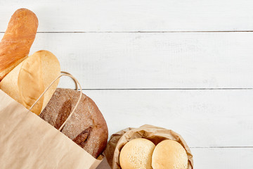 Whole grain bread in ecology paper bag on white wooden background. Save ecology , Zero waste...