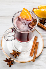 Mulled wine with cinnamon and orange in a glass transparent glass.