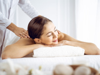 Obraz na płótnie Canvas Beautiful brunette woman enjoying back massage with closed eyes. Spa and medicine concept