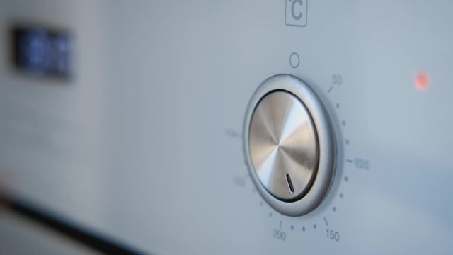 Closeup of female hand turns the oven switch sets temperature