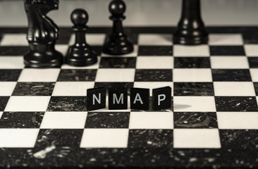 Nmap the word or concept represented by black and white letter tiles on a marble chessboard with chess pieces
