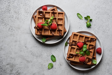 Belgian chocolate waffles decorated with mint and raspberries. Gray background, top view