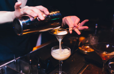 Bartender pouring using strainer White pink healthy Cocktail drink on a bar counter . Bartender view . Trendy stylish white. Copy paste for purple neon design people luxury service barman in nightclub