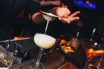 Bartender pouring using strainer White pink healthy Cocktail drink on a bar counter . Bartender view . Trendy stylish white. Copy paste for purple neon design people luxury service barman in nightclub