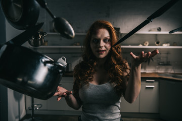 creepy demoniacal girl with levitating kitchenware in kitchen