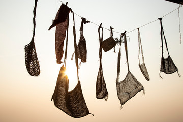 Bags and Clothing silhouette on clothesline with beautiful sunset as background.