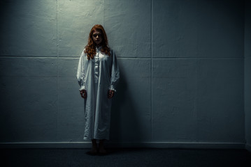 demonic obsessed girl in nightgown standing near wall