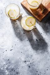 A short glass of refreshing pear soda water mocktail or cocktail on gray concrete background. Non alcoholic summer drink. Vertical orientation, copy space, top view, flat lay