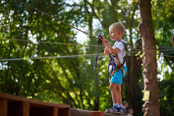 Little boy overcomes the obstacle in the rope park.