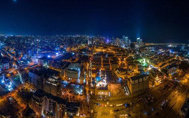 Fototapeta premium Bejrut, Liban 2019: Panoramiczne ujęcie lotnicze z drona centrum Bejrutu na pierwszym planie i panoramę miasta w nocy w tle.