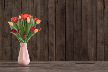 tulips in vase on dark wooden background