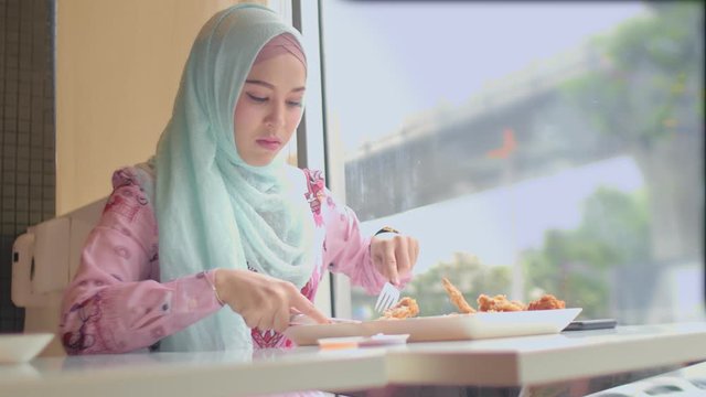 .Islamic lady eating fried chicken in restaurant beside the road in Bangkok city Thailand