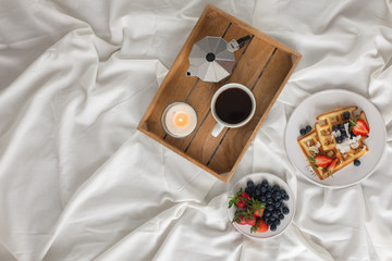 Beautiful breakfast in bed: Viennese Belgian waffles decorated with berries, a plate with strawberries and blueberries