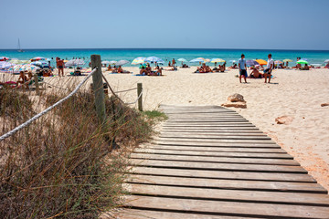A wooden walkway leads to a sandy beach in Formentera in the Balearic islands of Spain.