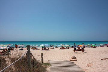 A wooden walkway leads to a sandy beach in Formentera in the Balearic islands of Spain.