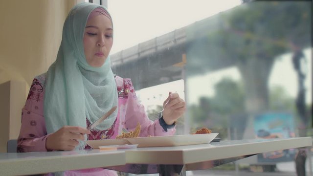 .Islamic lady eating fried chicken in restaurant beside the road in Bangkok city Thailand