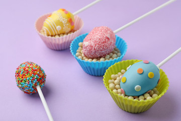 Egg shaped cake pops for Easter celebration on violet background, closeup