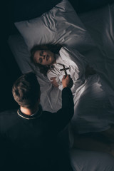 exorcist holding cross over obsessed girl in bed