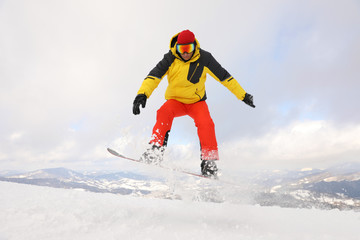 Naklejka na ściany i meble Male snowboarder on snowy hill. Winter vacation