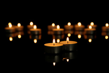 Burning candles on table against dark background