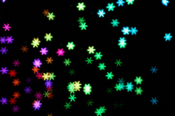 Fototapeta na wymiar Blurred view of colorful lights on black background. Bokeh effect
