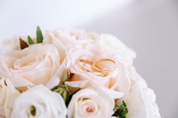 wedding gold rings lie on the petals of a bouquet of pink roses. close up