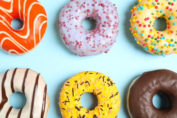 Delicious glazed donuts on light blue background, flat lay