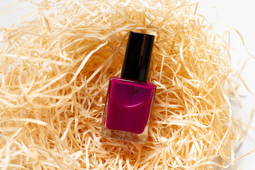 a purple nail polish in wood shavings