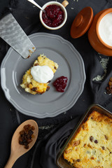 Cottage cheese casserole with raisins on a gray plate, poured sour cream on top. Flat lay, view from above. 