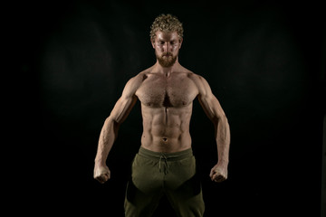 Fototapeta premium Beautiful muscles, athletic body. Studio photography on a black background, naughty light. Combat sport. Fair-haired sports man