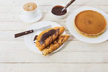 pancakes with chocolate and coffee on white wooden background