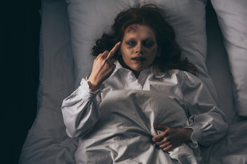 top view of demonic girl in nightgown showing middle finger