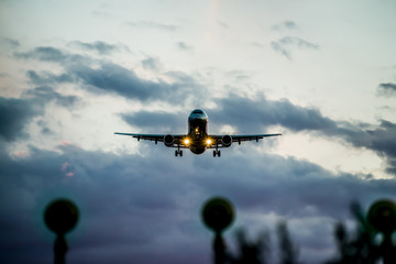 Front view of a commercial airplane with turned on landing lights landing on an airport.