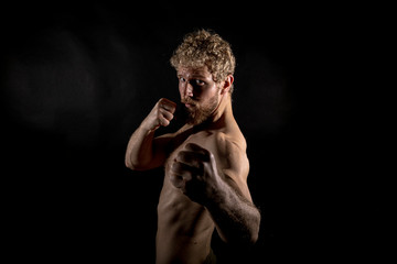 Fototapeta na wymiar Beautiful muscles, athletic body. Studio photography on a black background, naughty light. Combat sport. Fair-haired sports man
