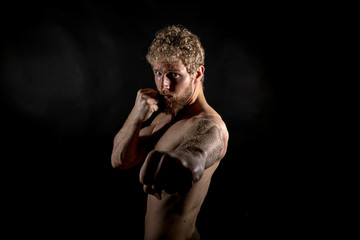 Fototapeta na wymiar Beautiful muscles, athletic body. Studio photography on a black background, naughty light. Combat sport. Fair-haired sports man