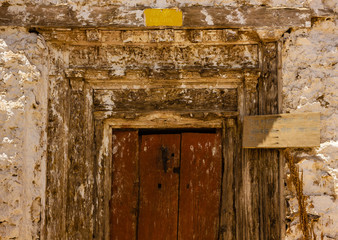 A wooden door to a shrine with faded carvings inside the ancient Buddhist monastery at Nako in Kinnaur, India. The text in Hindi says "Women not allowed inside".