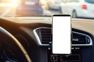 Modern smartphone device gadget mounted on phone holder at car dashboard. Mock-up white screen...