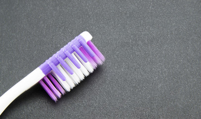 Close-up of the head of a pink and white toothbrush on a black textured background. Good quality