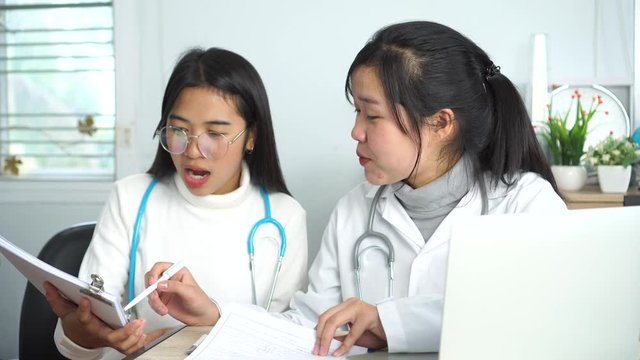 Medical student,Online doctoring,Asian female teenage doctor intern working healthcare medical teamwork for discussing patients records on laptop computer sitting on desk consultation hospital