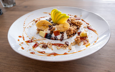 Granola with yogurt, fruit and nuts on a white dish