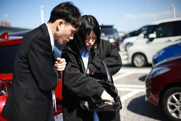 駐車場で車の鍵を捜すカップル