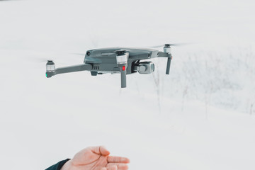 A young man launches a drone into the air in winter in the forest.
